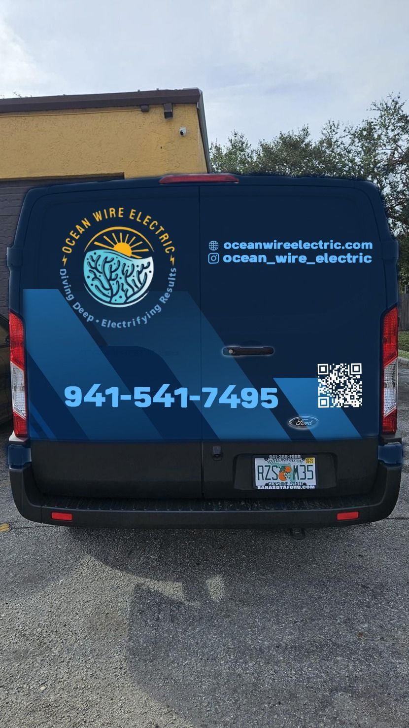 A blue van with a phone number on the back is parked in a parking lot.