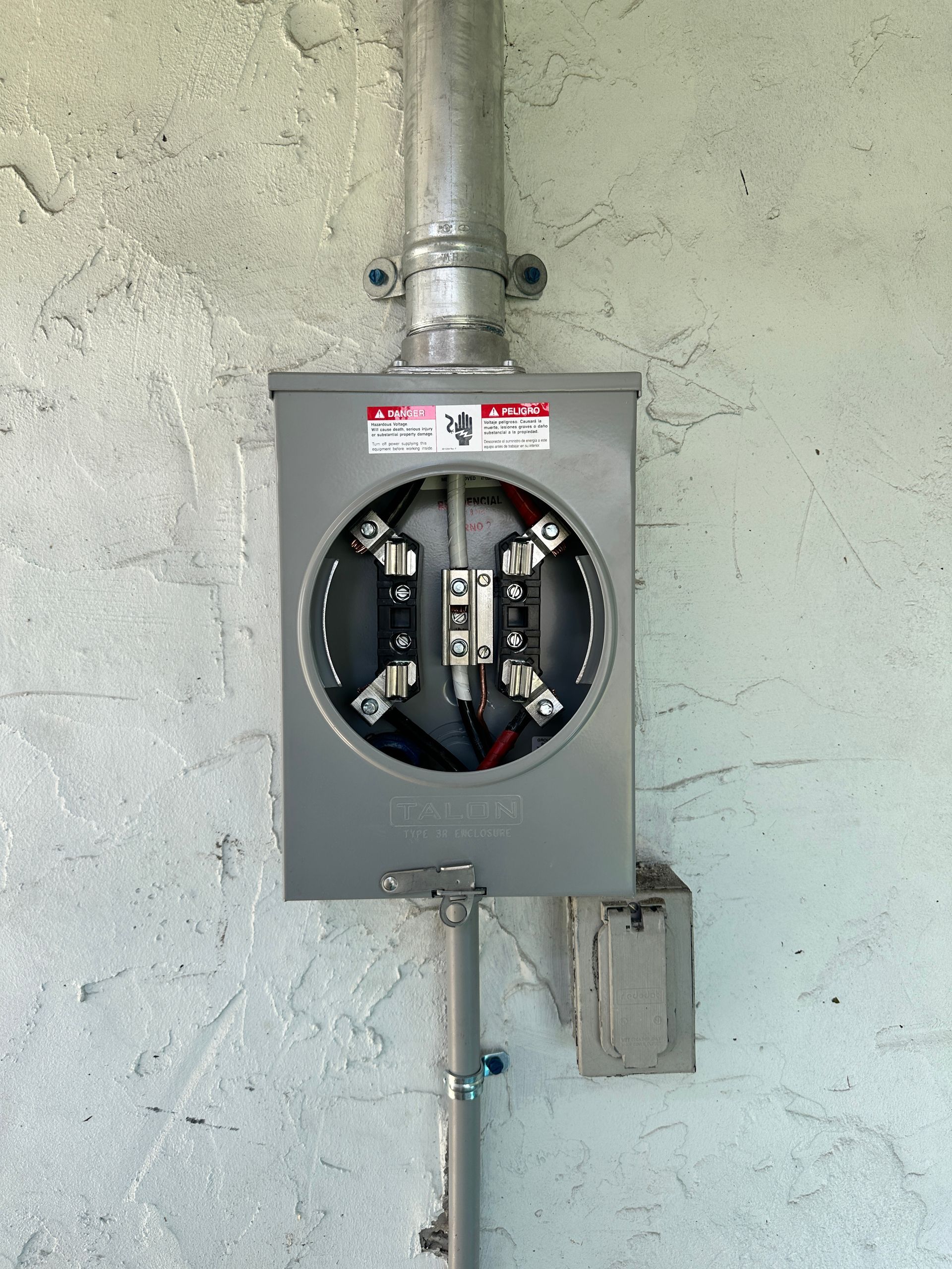 Electrical installation with open meter box and wiring setup for home power supply and electrical panel connection.