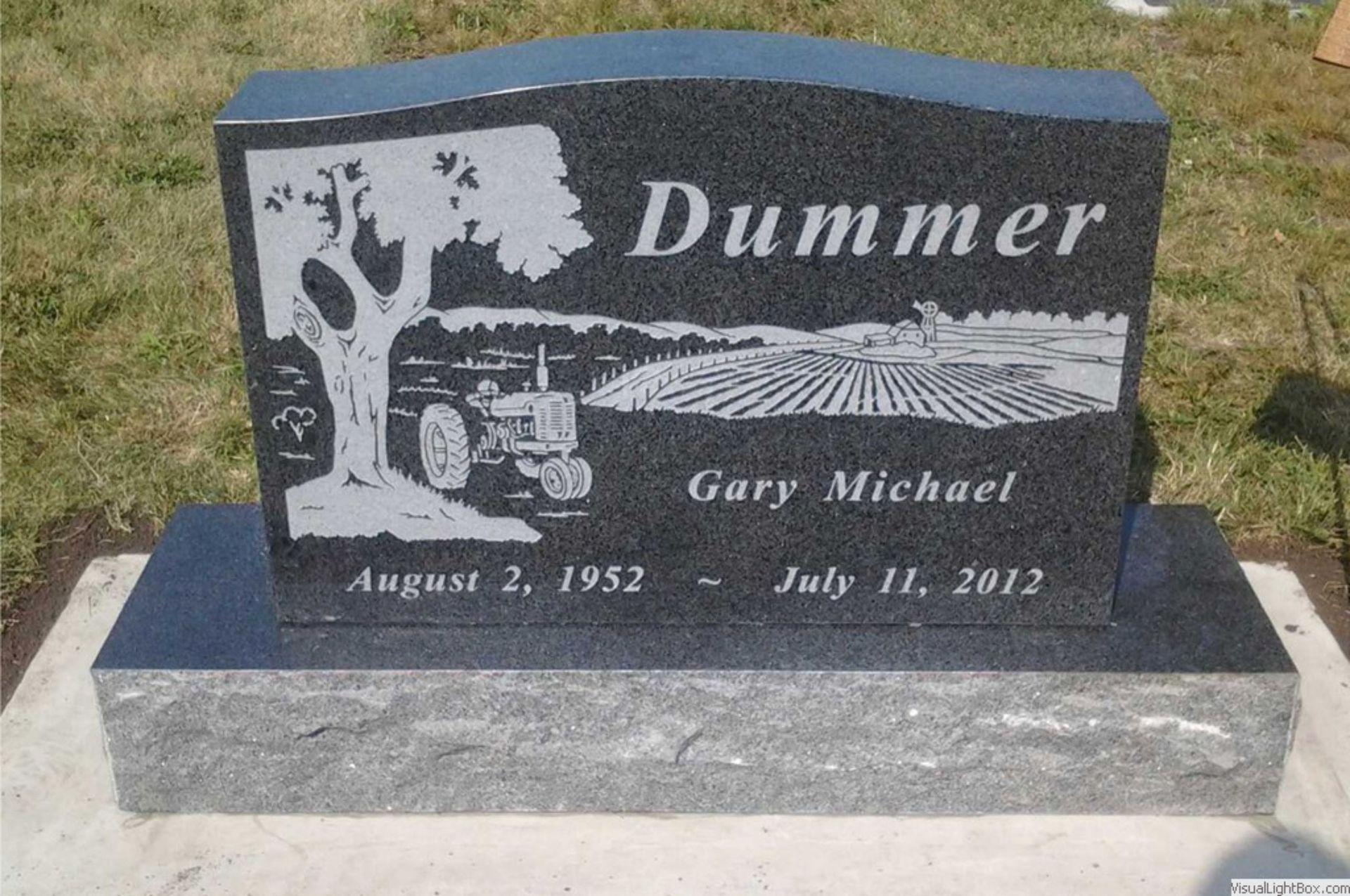 Monument with a colorful landscape scene, black base, and a gray textured lower base.