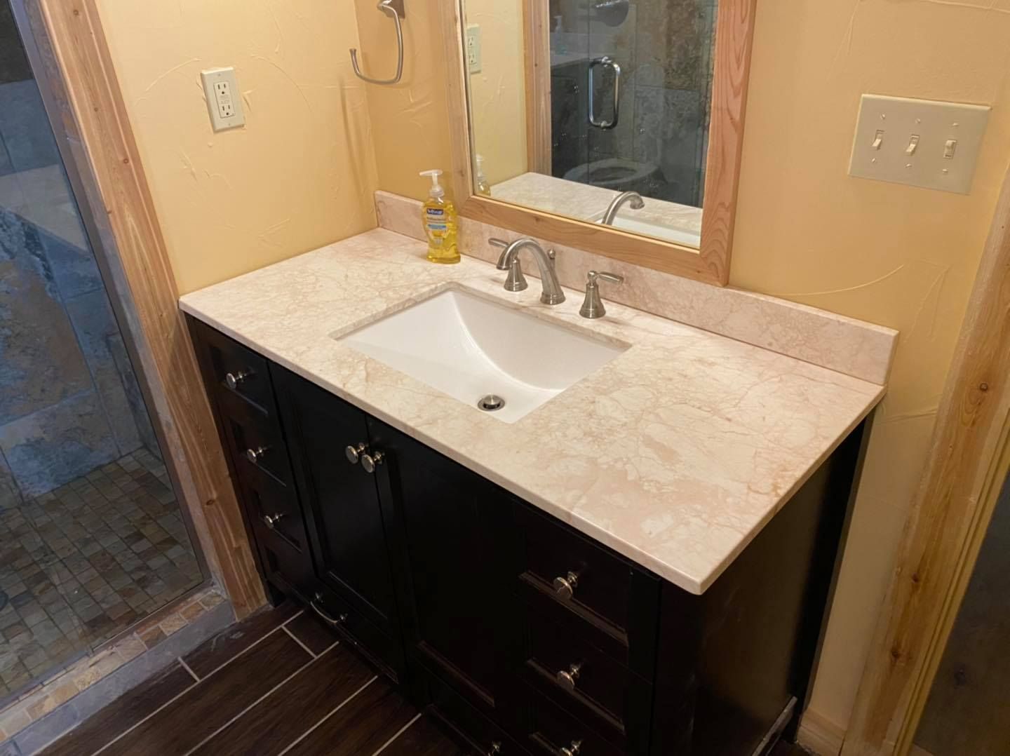 A bathroom with a sink , mirror and drawers.