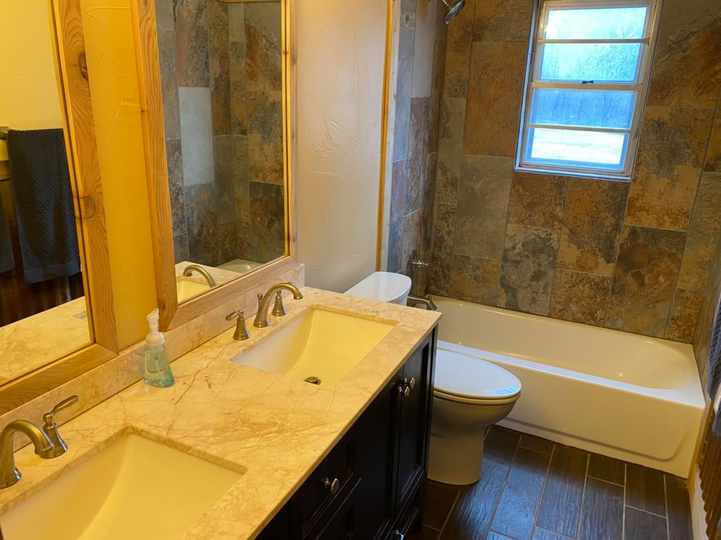 A bathroom with two sinks , a toilet , and a tub.
