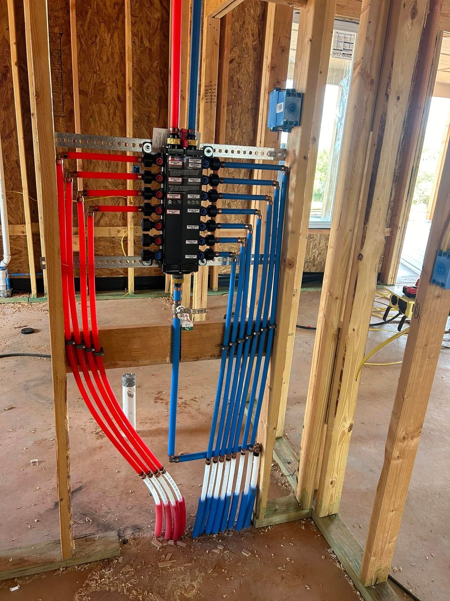 A bunch of pipes are hanging from a wall in a house under construction.