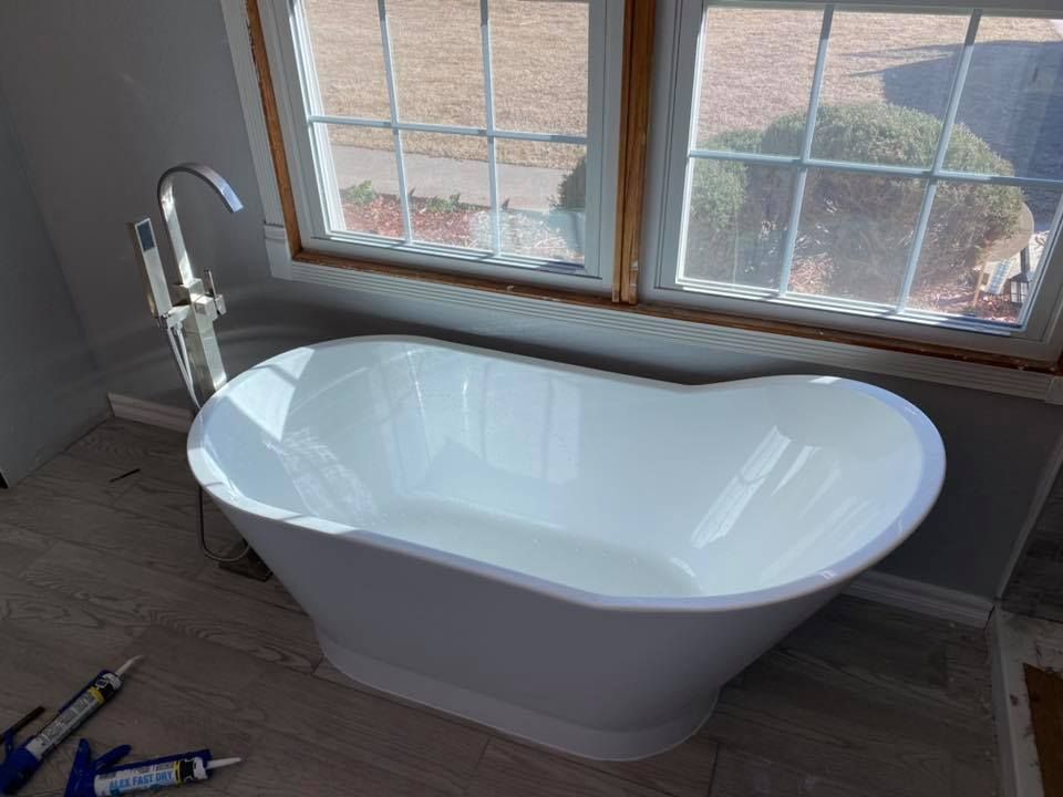 A white bathtub is sitting in a bathroom next to a window.