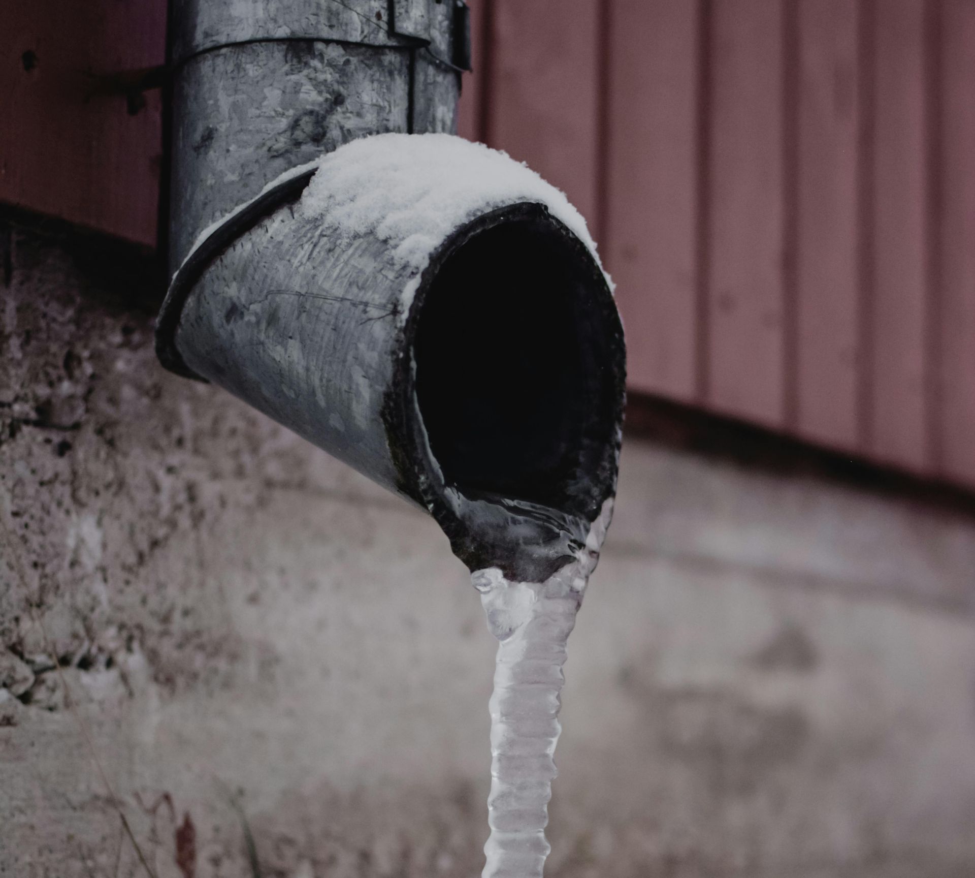 A drainpipe with snow and ice coming out of it