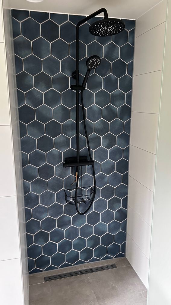 Een douche met blauwe tegels en een zwarte douchekop. Vakantiewoning Boshuisje de Leeuwerik