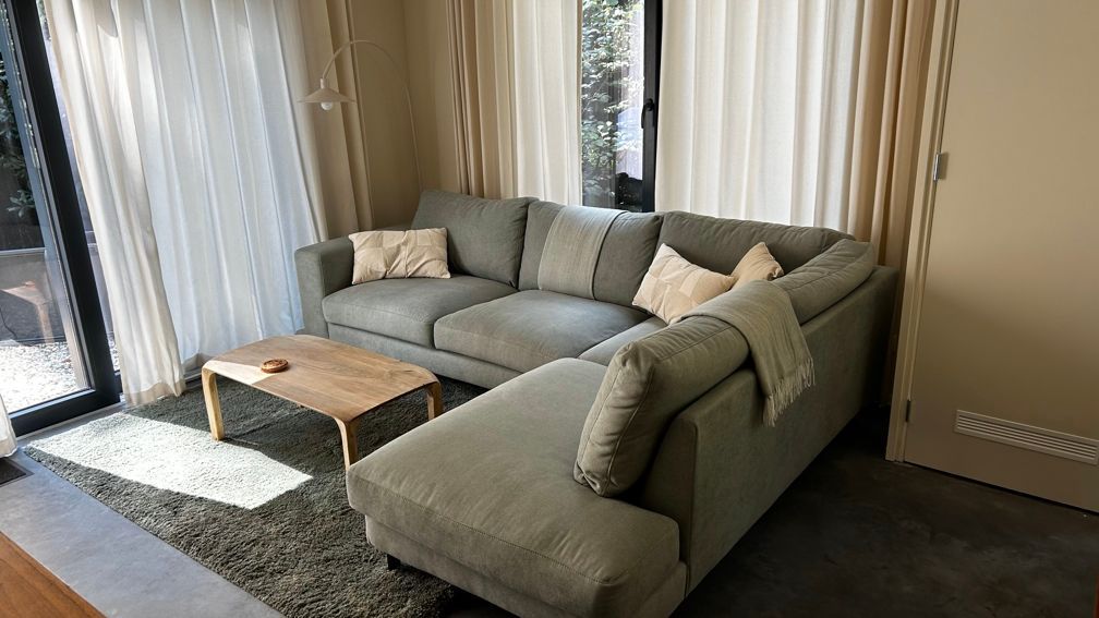 Een woonkamer met een hoekbank en een salontafel. Vakantiewoning Boshuisje de Leeuwerik