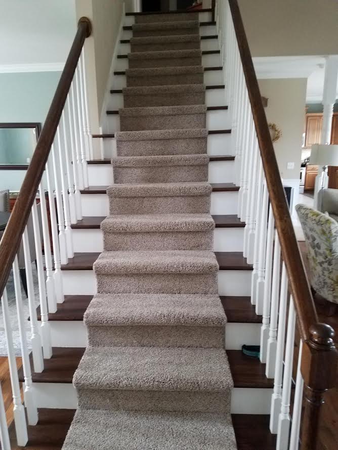 A staircase with carpeted steps and a wooden railing