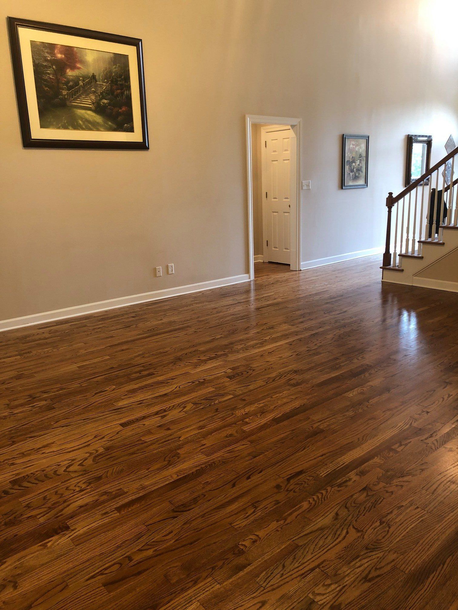 An empty living room with hardwood floors and a picture on the wall.