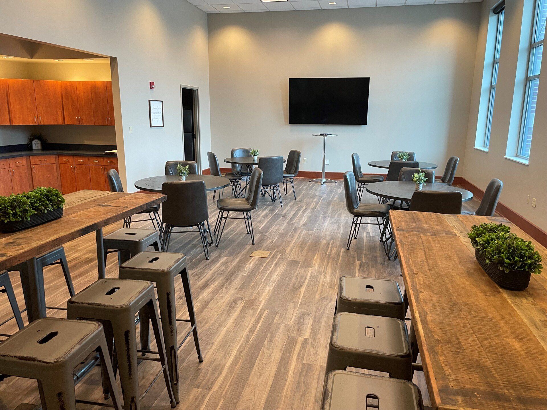 A large room with tables and chairs and a flat screen tv.