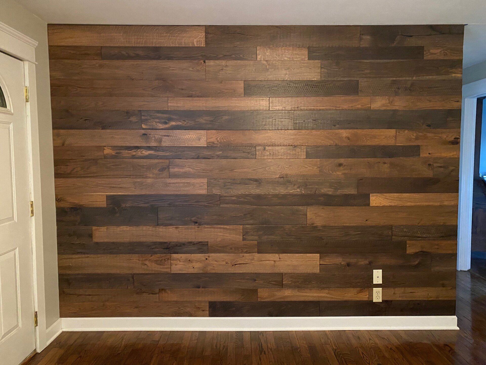 A room with a wooden wall and hardwood floors.