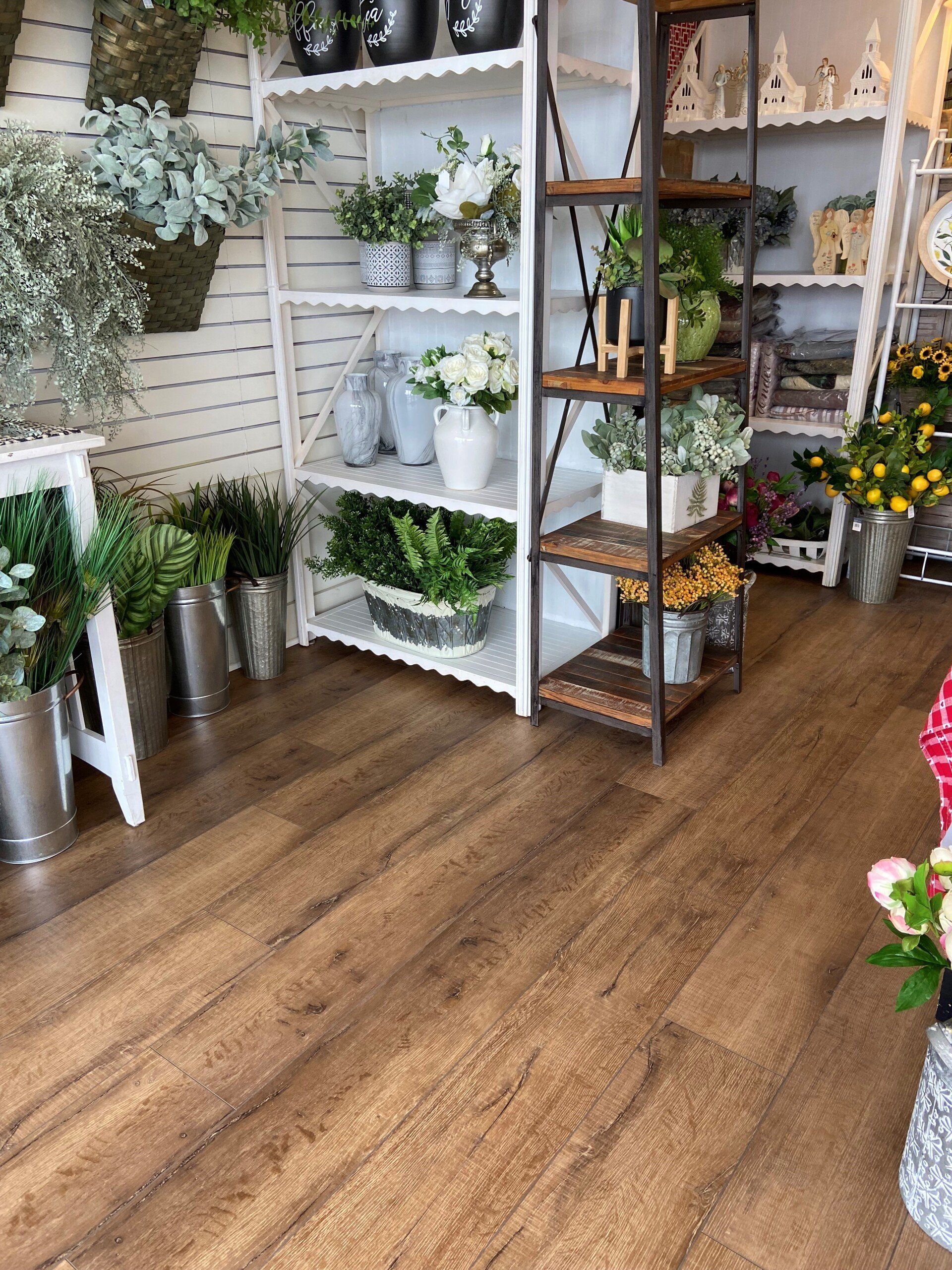 A room filled with shelves filled with potted plants and flowers.