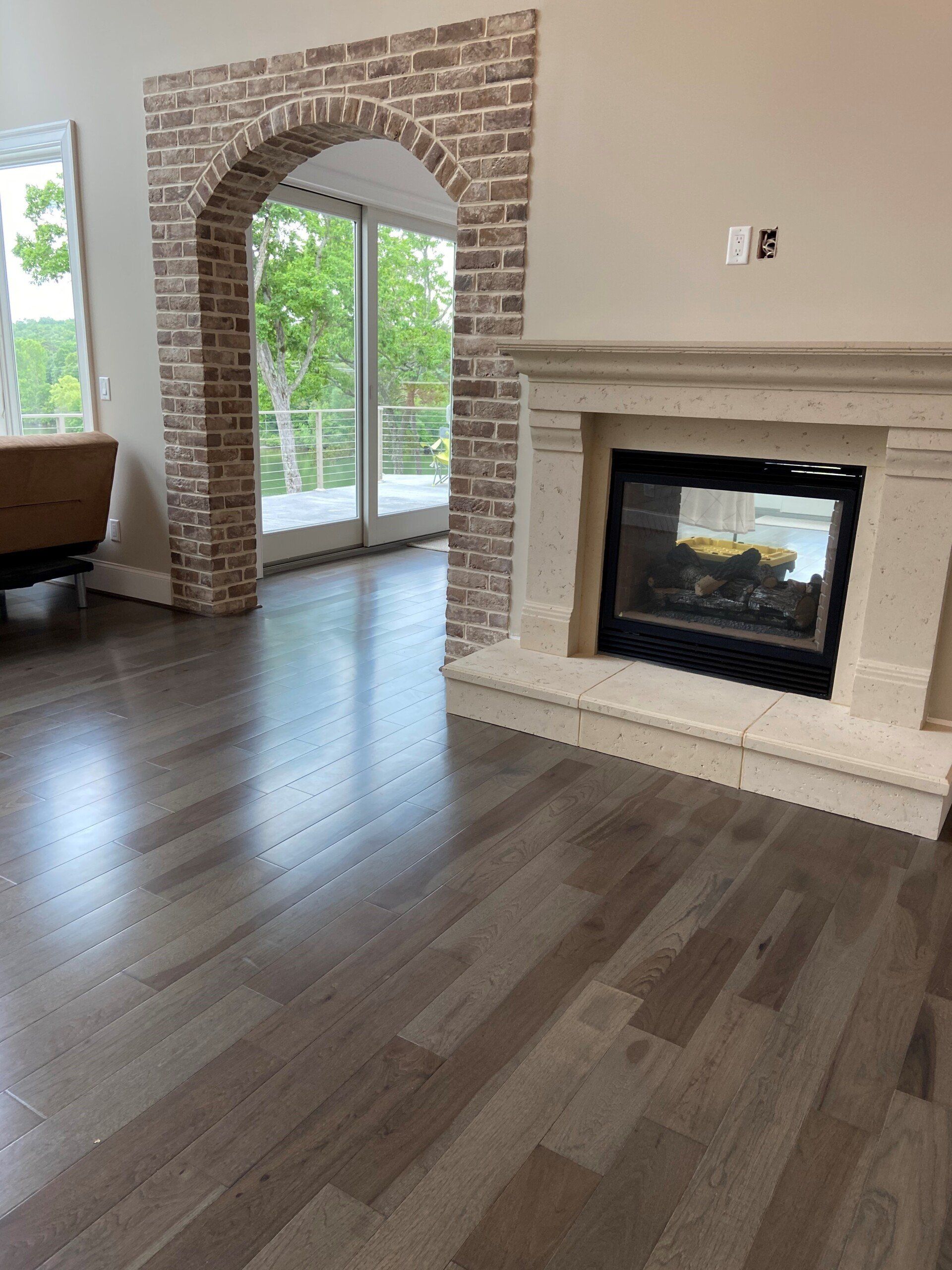 A living room with a fireplace and a brick archway.