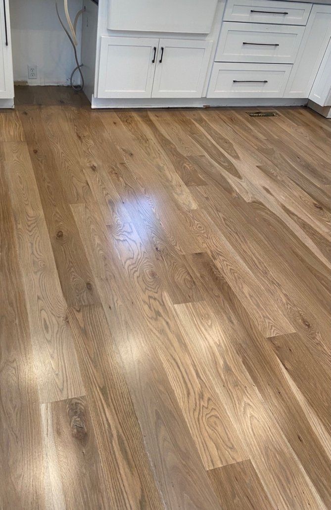 A kitchen with hardwood floors and white cabinets.