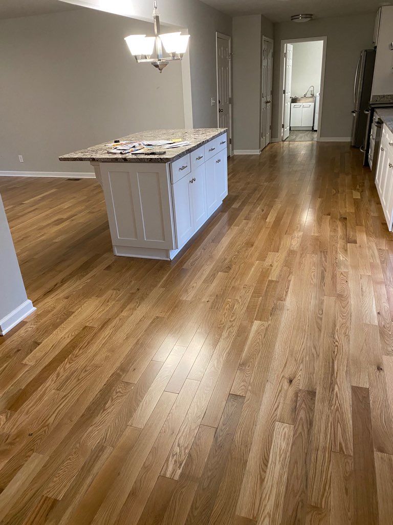 A kitchen with hardwood floors and a large island in the middle.