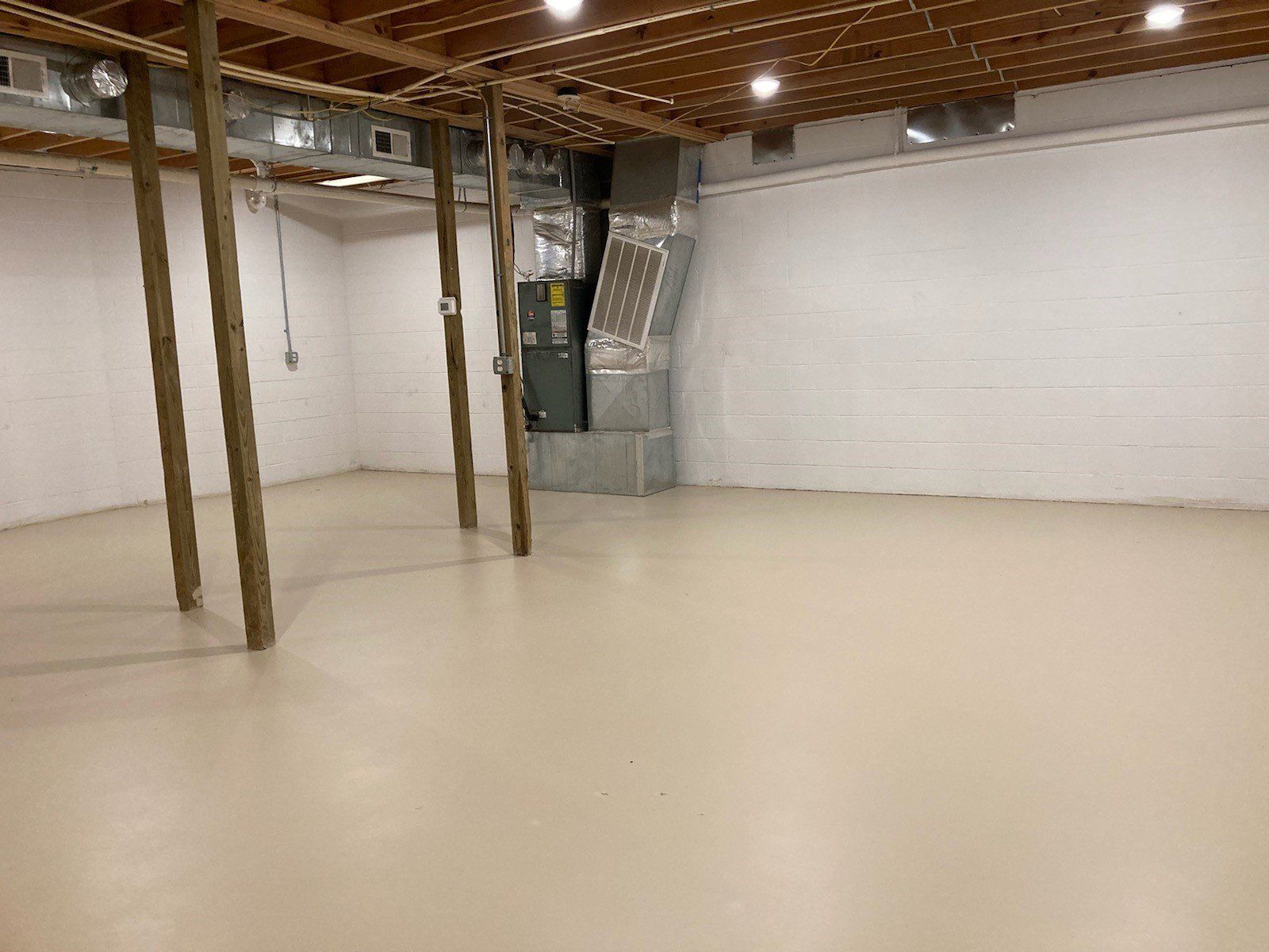 An empty basement with a wooden ceiling and white walls.