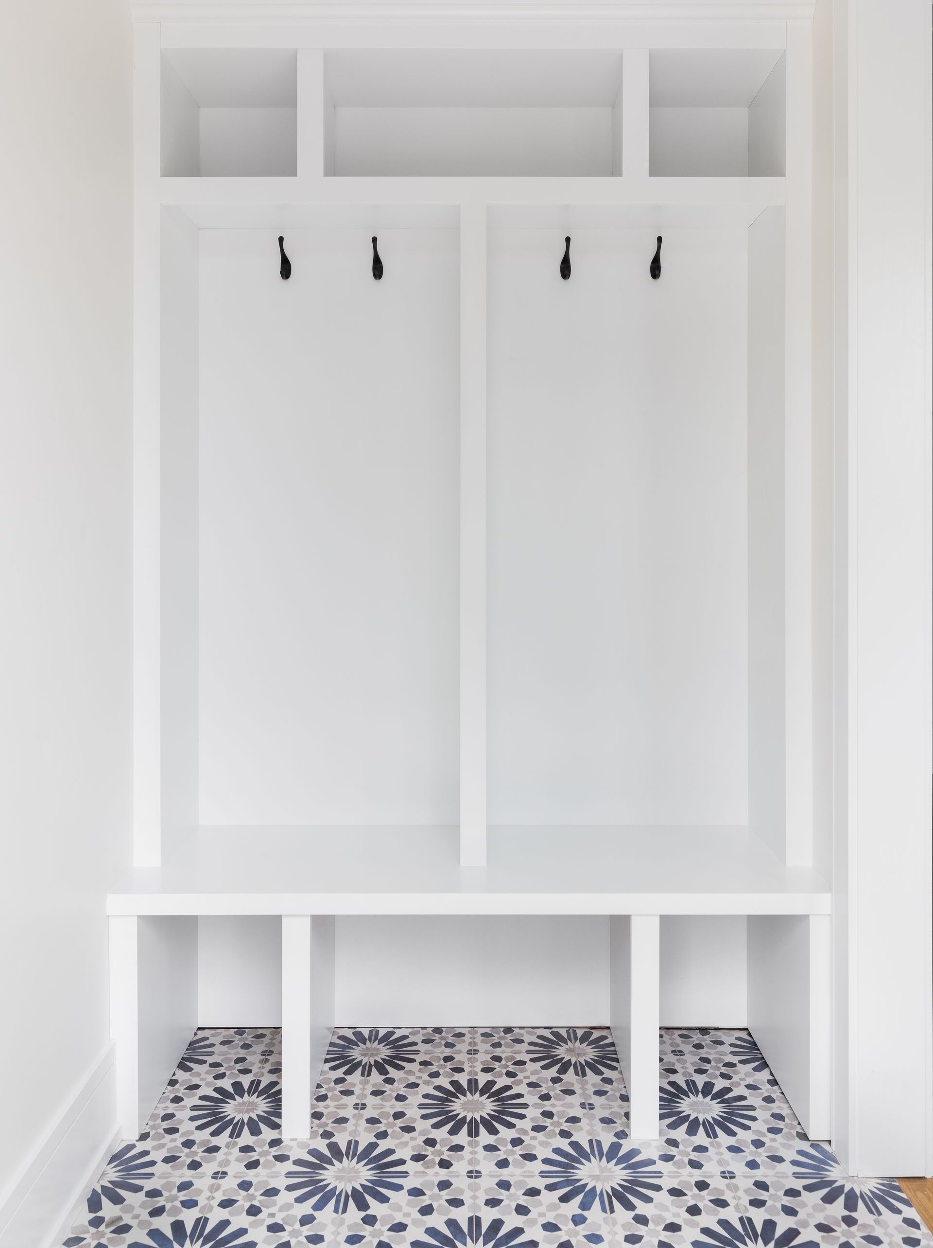 A hallway with a bench and hooks on the wall