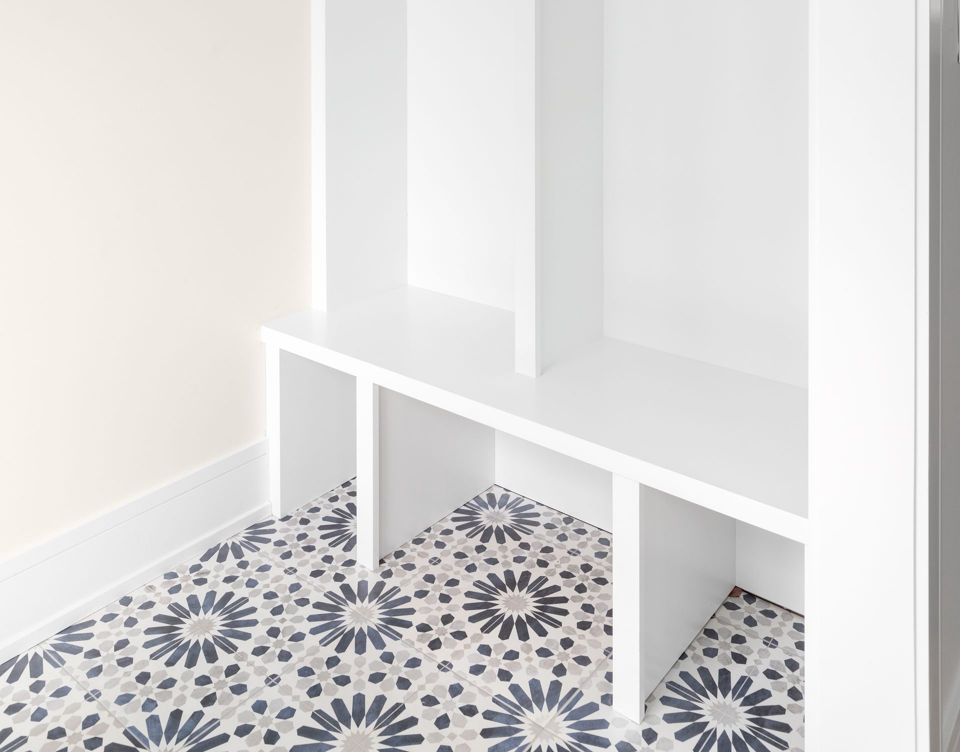A white shelf with a patterned floor in a room.