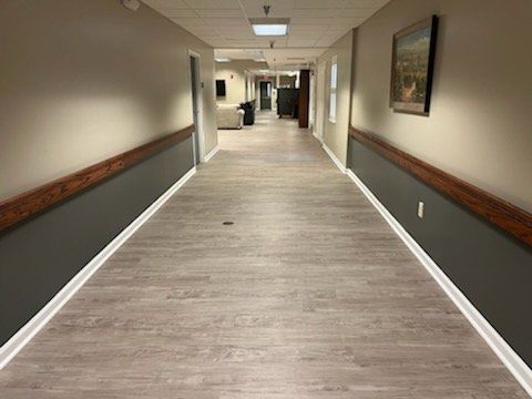 A long hallway with wooden floors and a picture on the wall.
