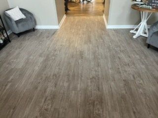 A living room with a wooden floor and two chairs.