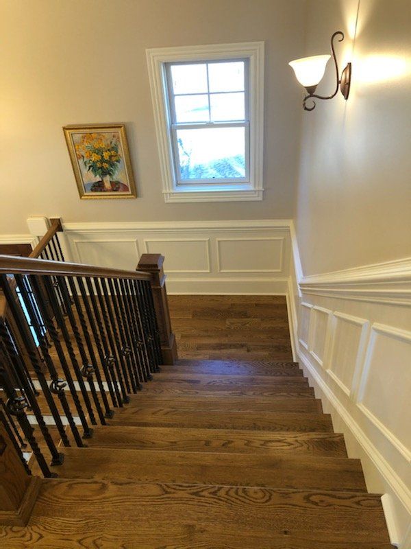 A wooden staircase with a black railing and a window
