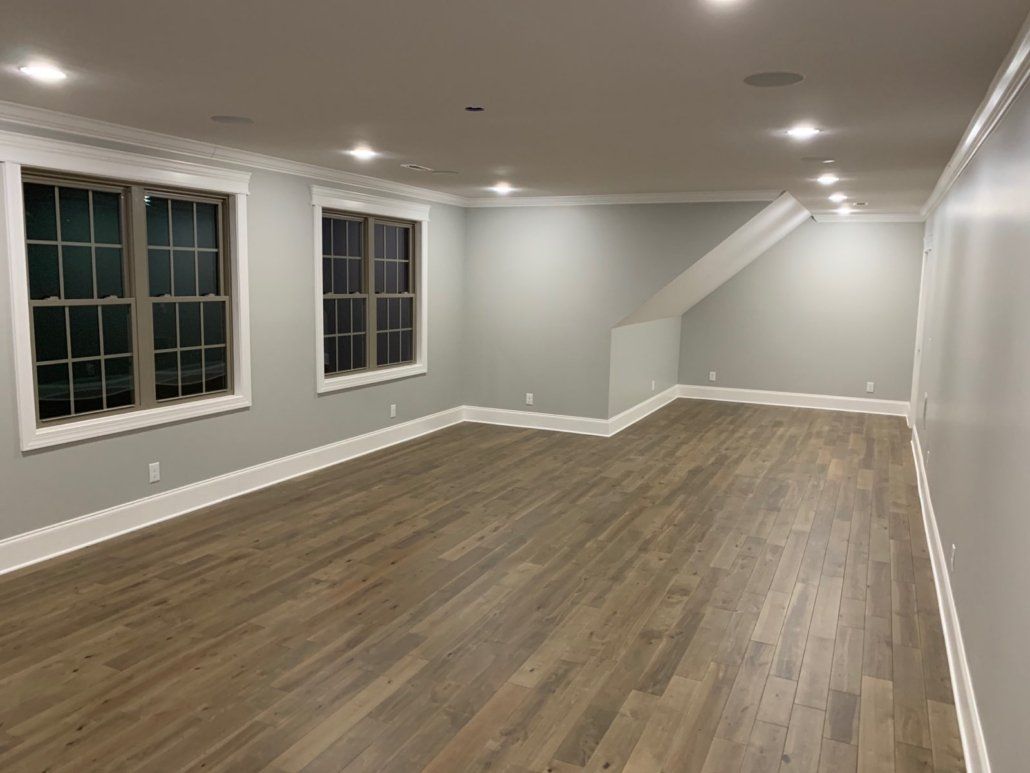 An empty room with hardwood floors and two windows