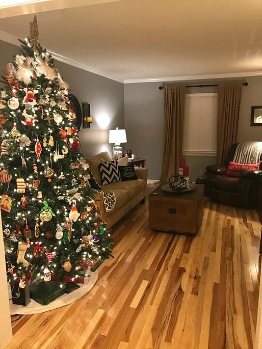 There is a christmas tree in the middle of the living room.