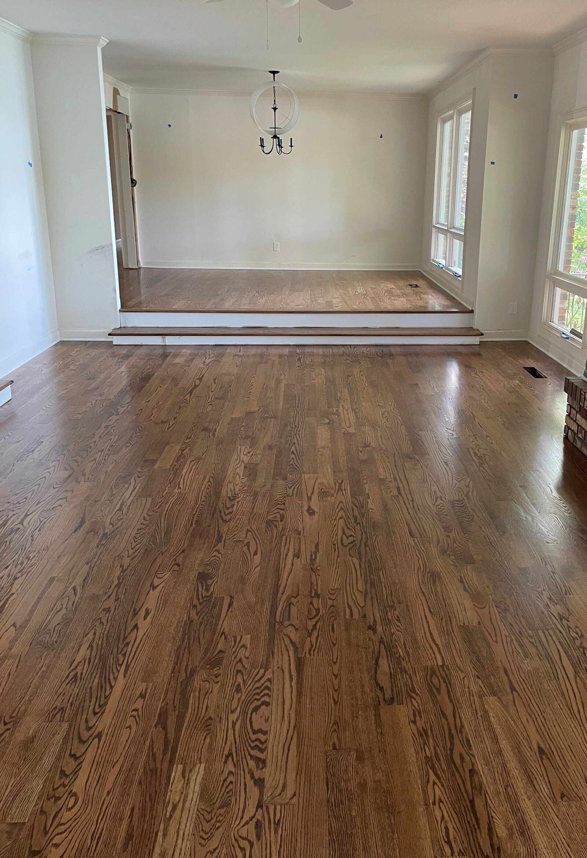 A living room with hardwood floors and white walls.