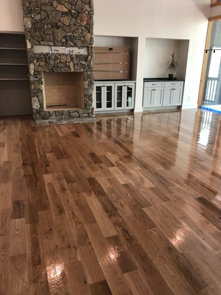 A living room with hardwood floors and a stone fireplace.