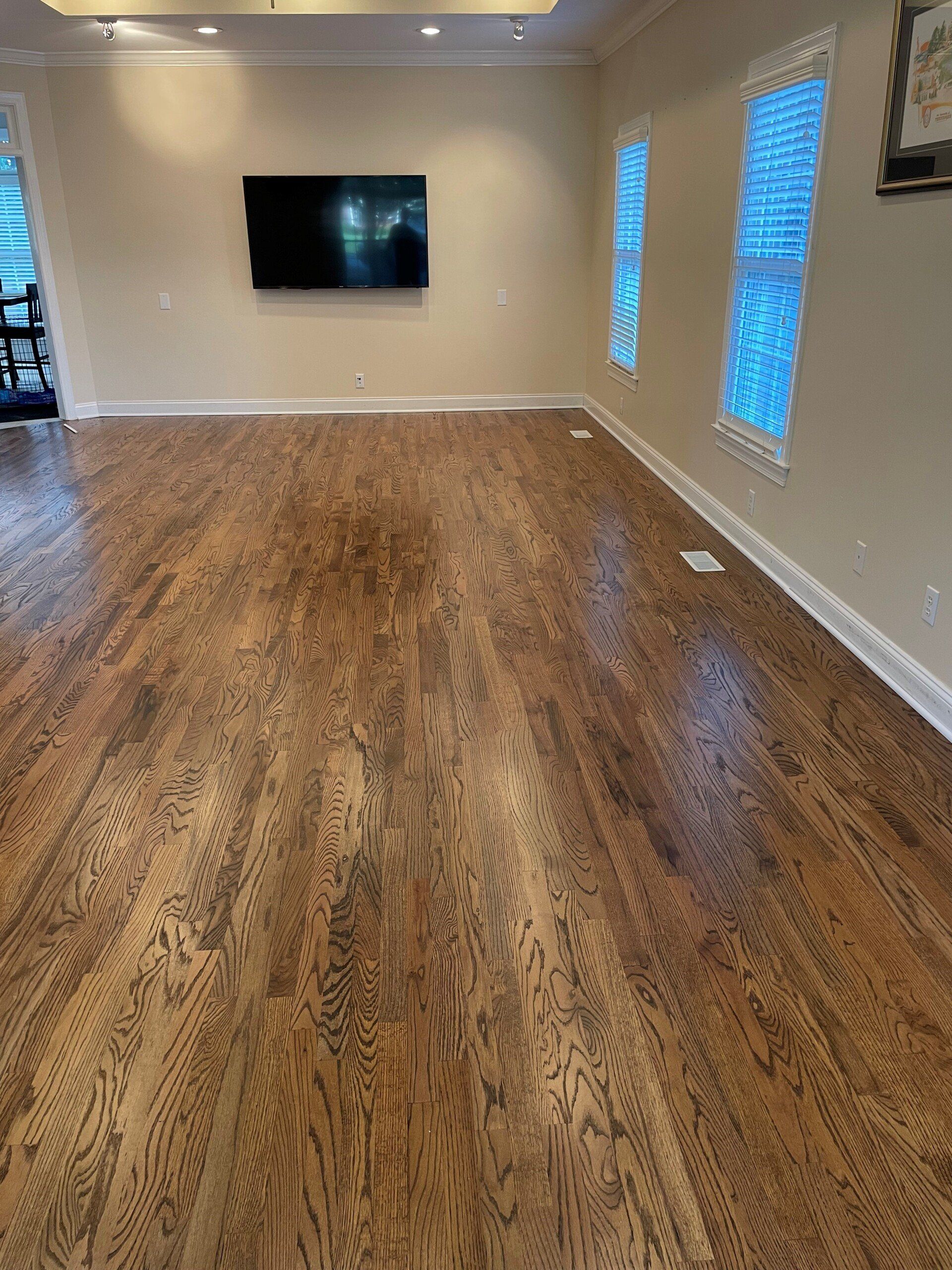 A living room with hardwood floors and a flat screen tv on the wall.
