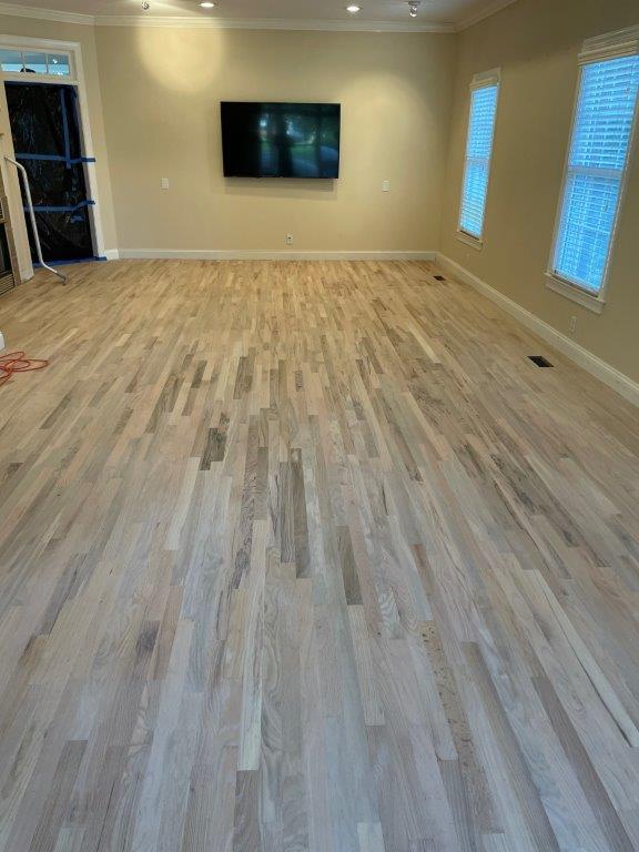 A living room with hardwood floors and a flat screen tv on the wall.