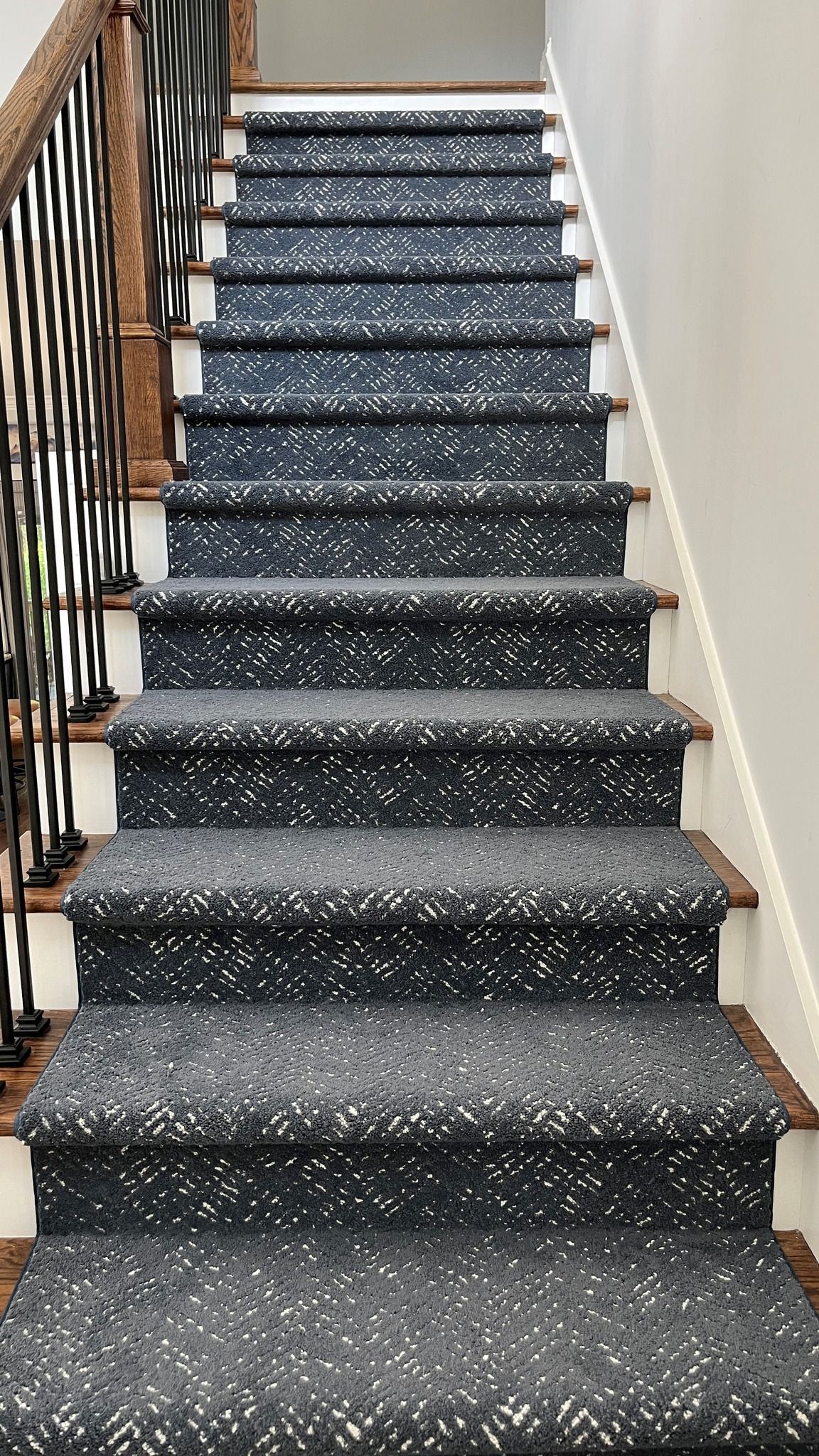 A staircase with a black carpet on the steps and a black railing.