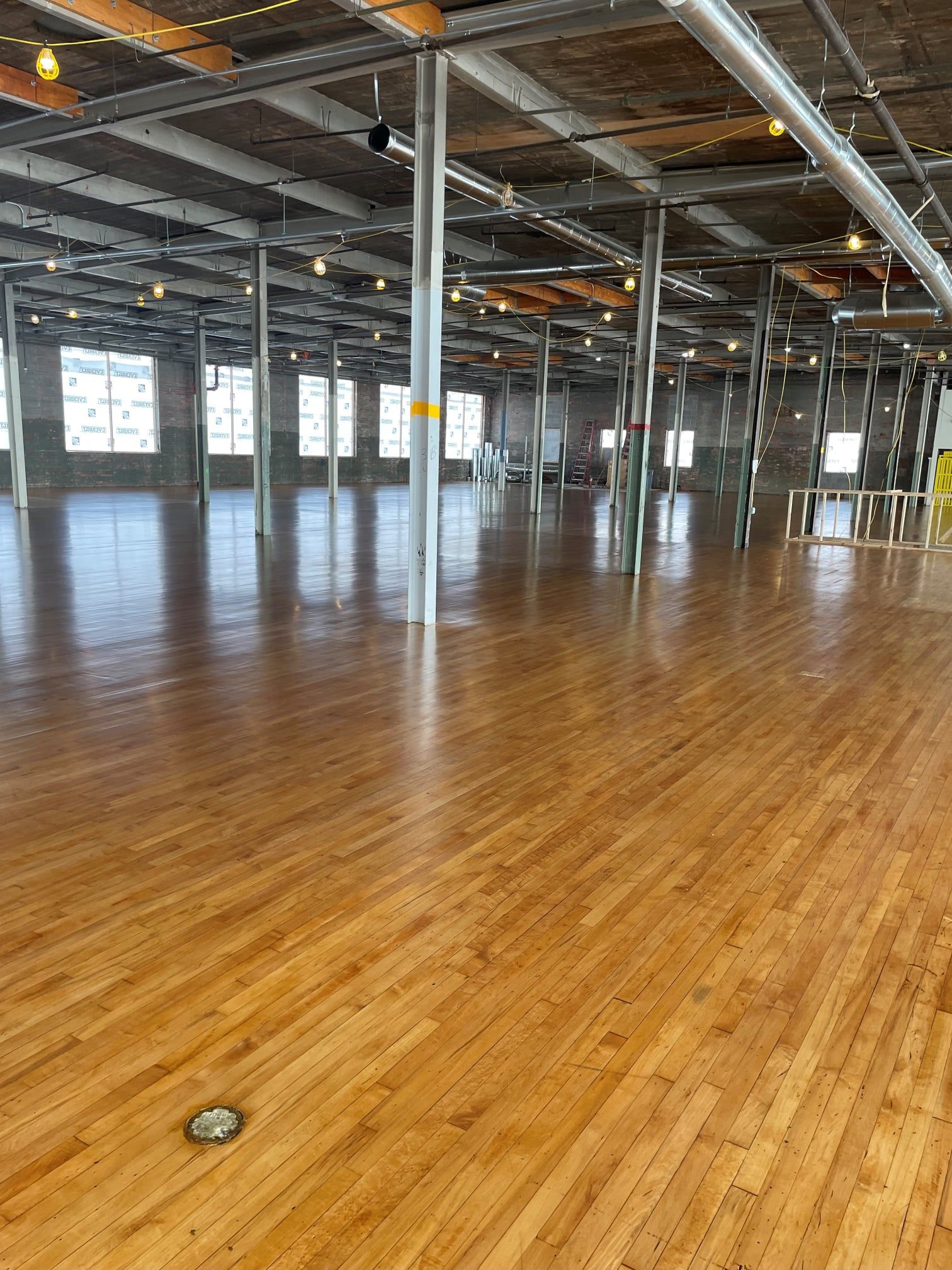A large empty room with wooden floors and a lot of windows.