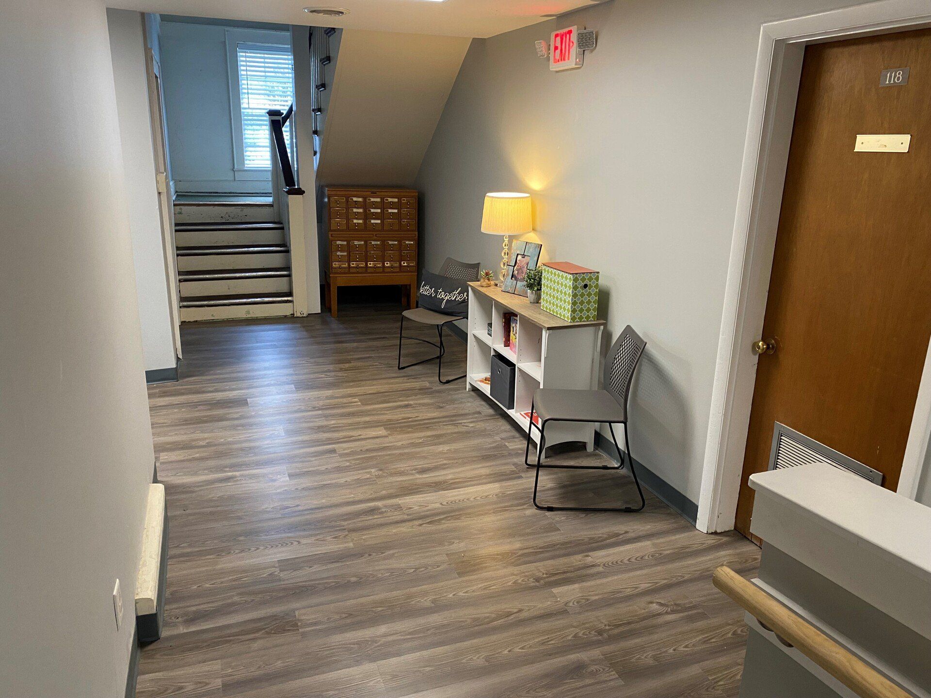 A hallway with wooden floors and stairs in a building.