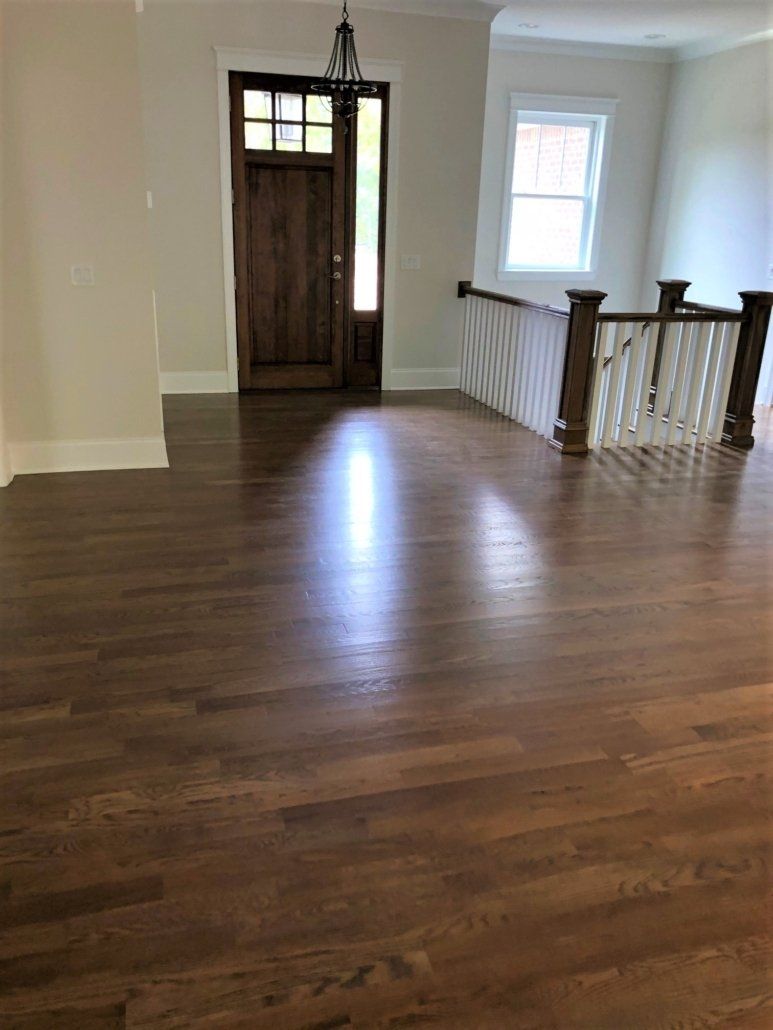 A large empty room with hardwood floors and a staircase.