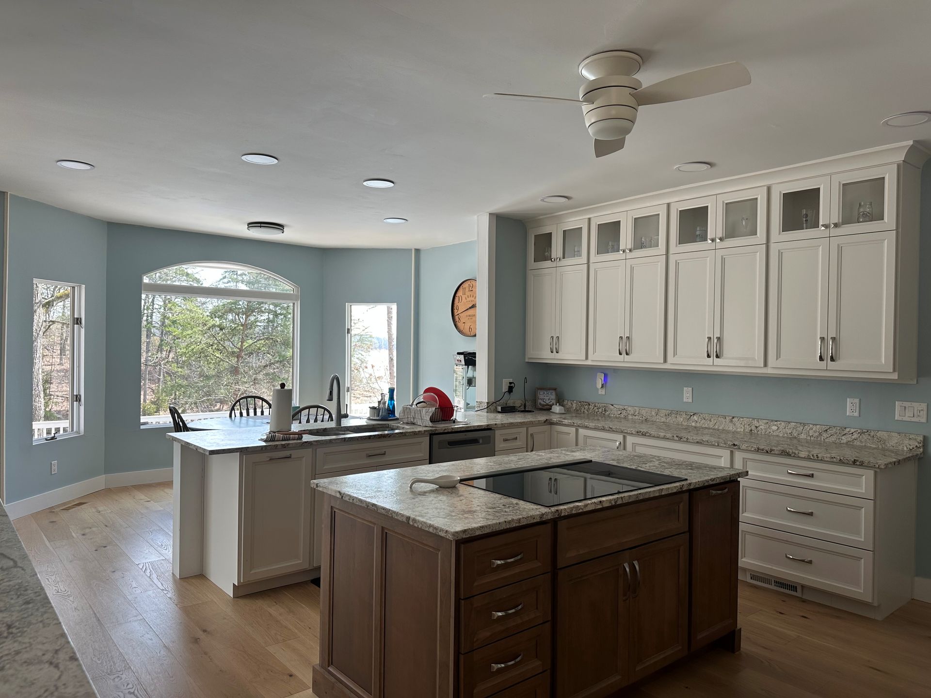 A kitchen with a large island in the middle and a ceiling fan.