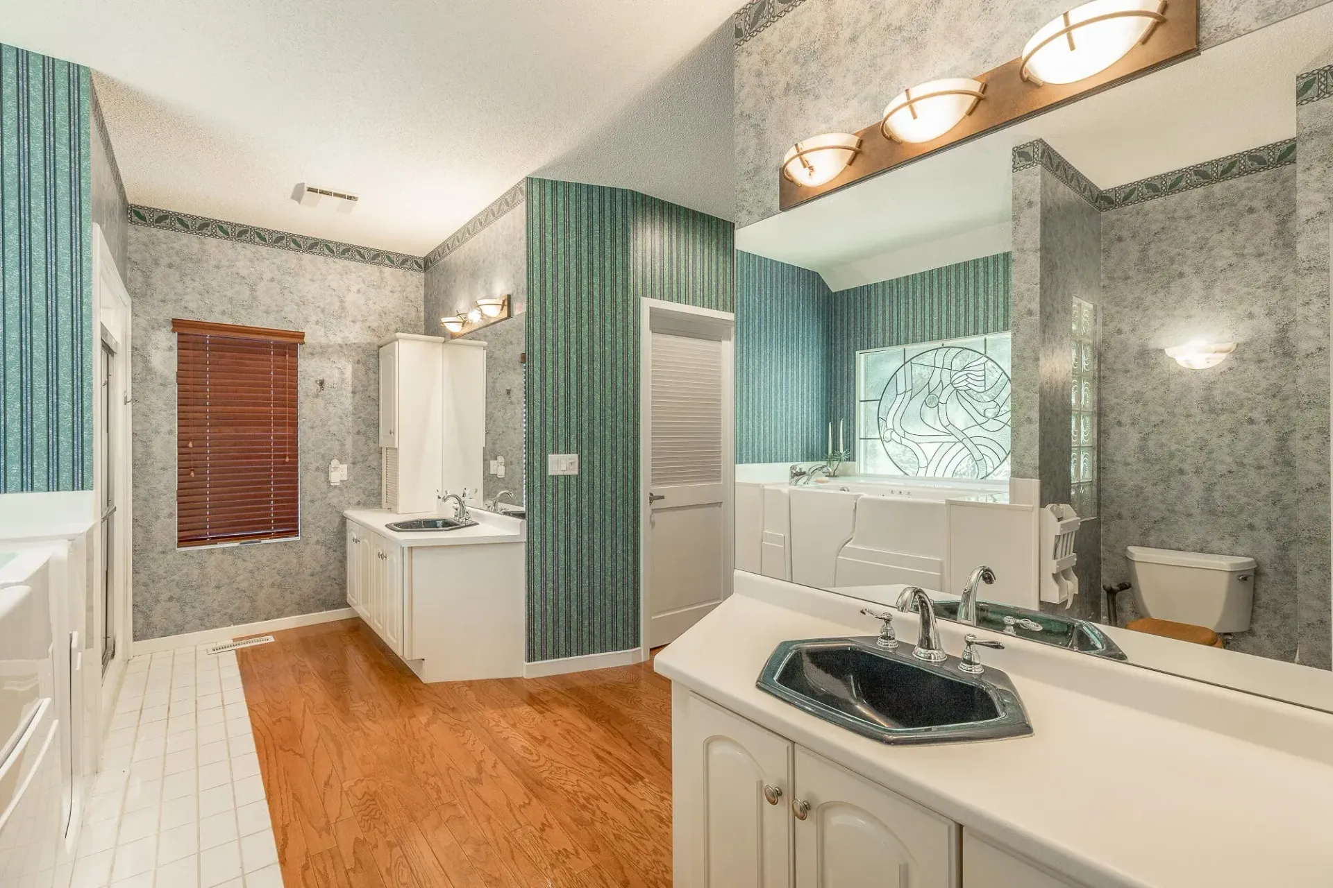A bathroom with two sinks , a toilet , and a large mirror.