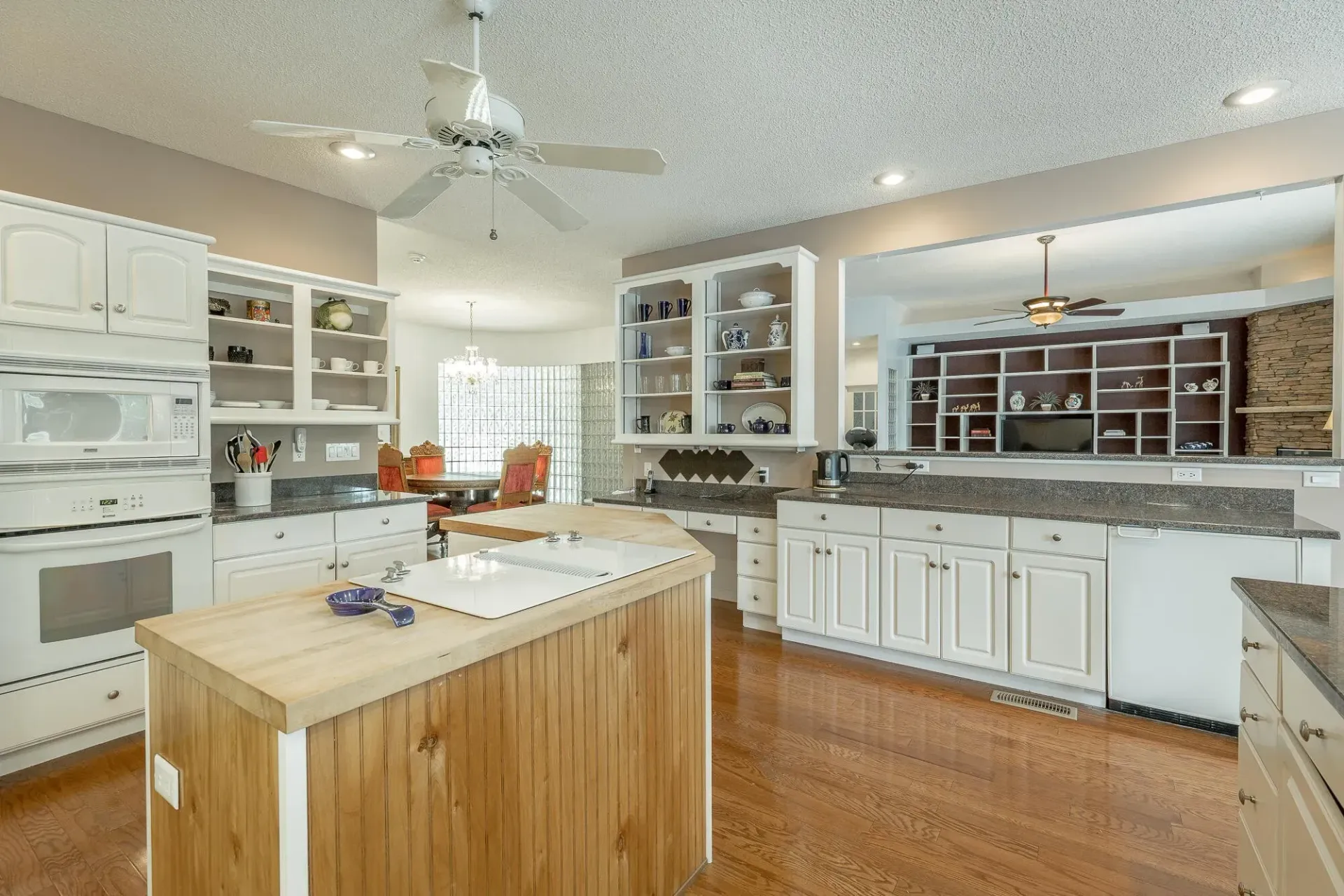 A kitchen with a large island in the middle and a ceiling fan.
