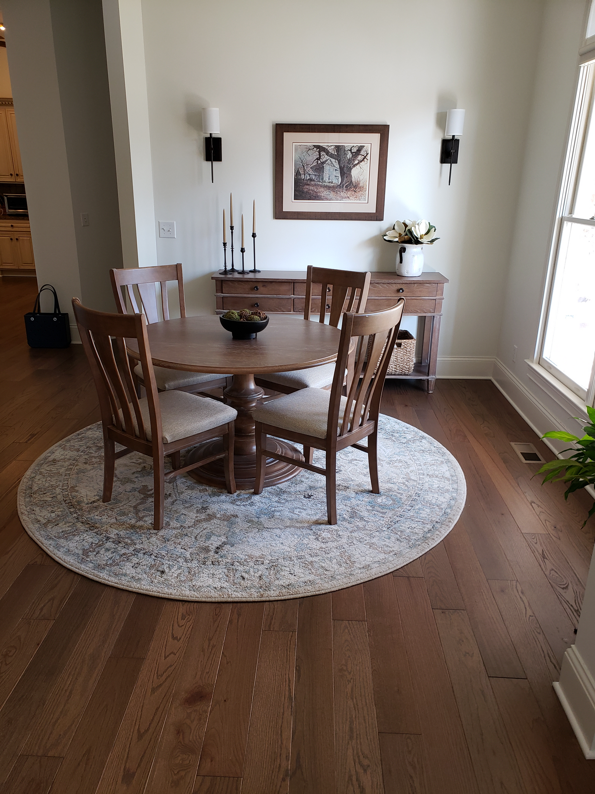 A dining room with a round table and chairs and a rug.