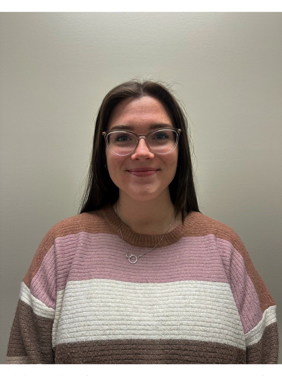 A woman wearing glasses and a striped sweater is smiling for the camera.