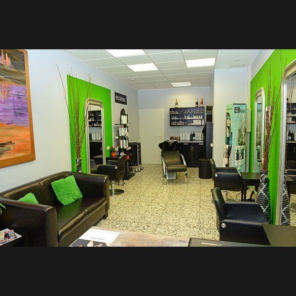 Ein Salon mit einer schwarzen Couch und grünen Kissen