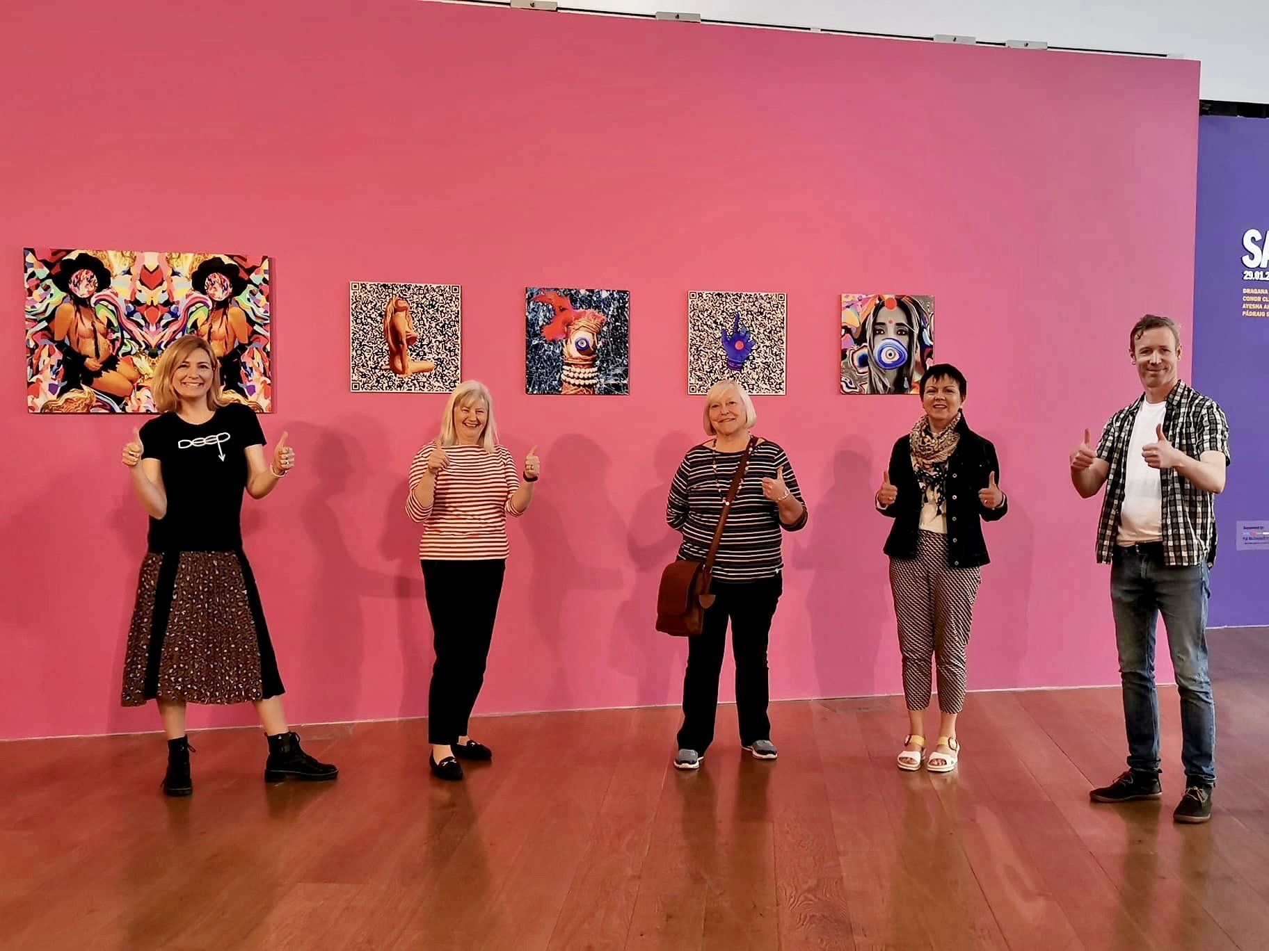 A group of people are standing in front of a pink wall.