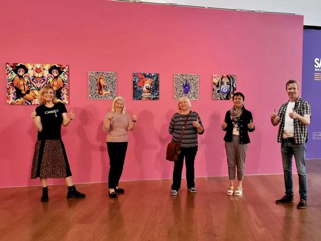 A group of people are standing in front of a pink wall.