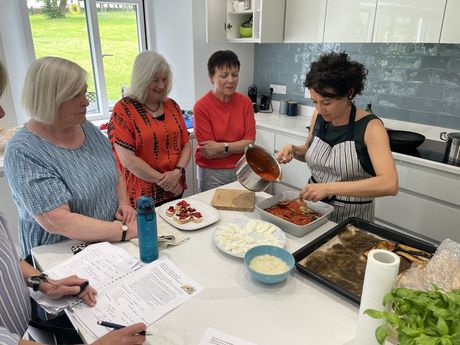 A group of women are sitting around a table in a kitchen preparing food.