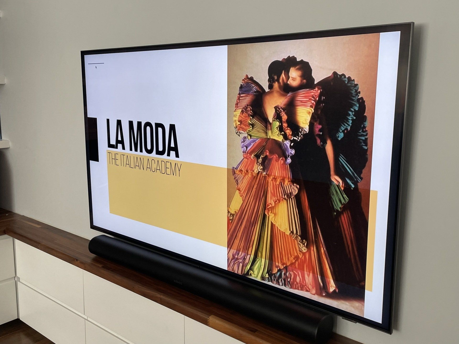 A flat screen tv is displaying a picture of a woman in a colorful dress