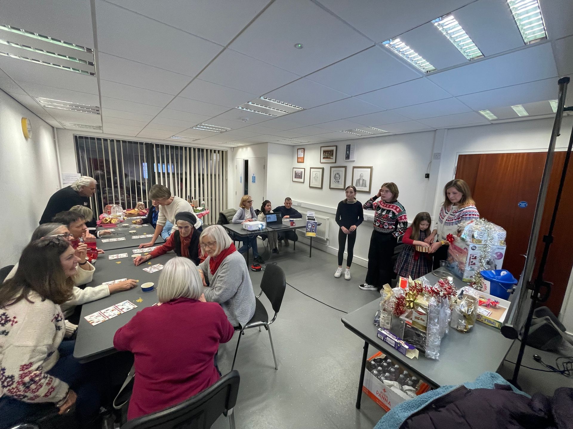 People playing games and socializing in a bright room, with gifts displayed.