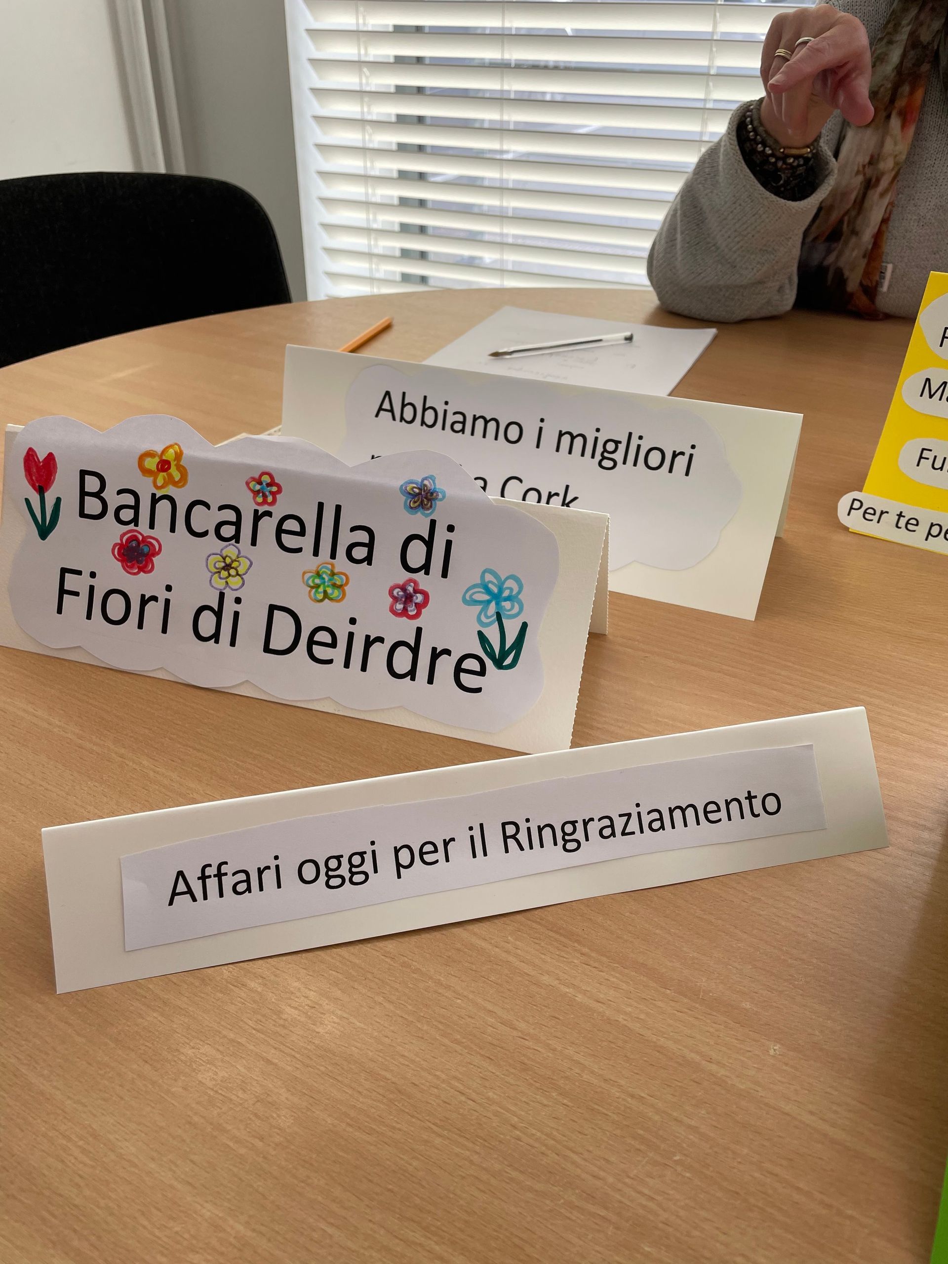 Three paper signs with Italian text and flower drawings on a table.