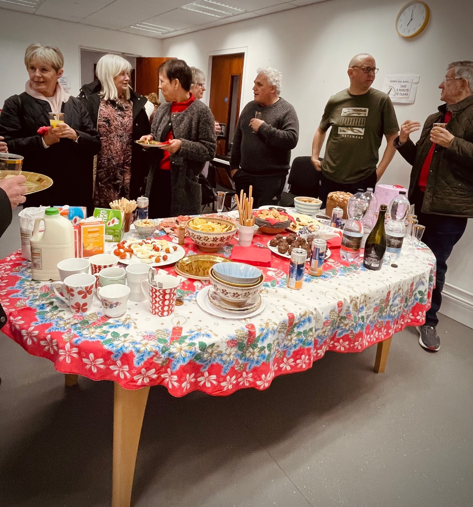 People gathered around a table laden with food. A party setting, indoors.