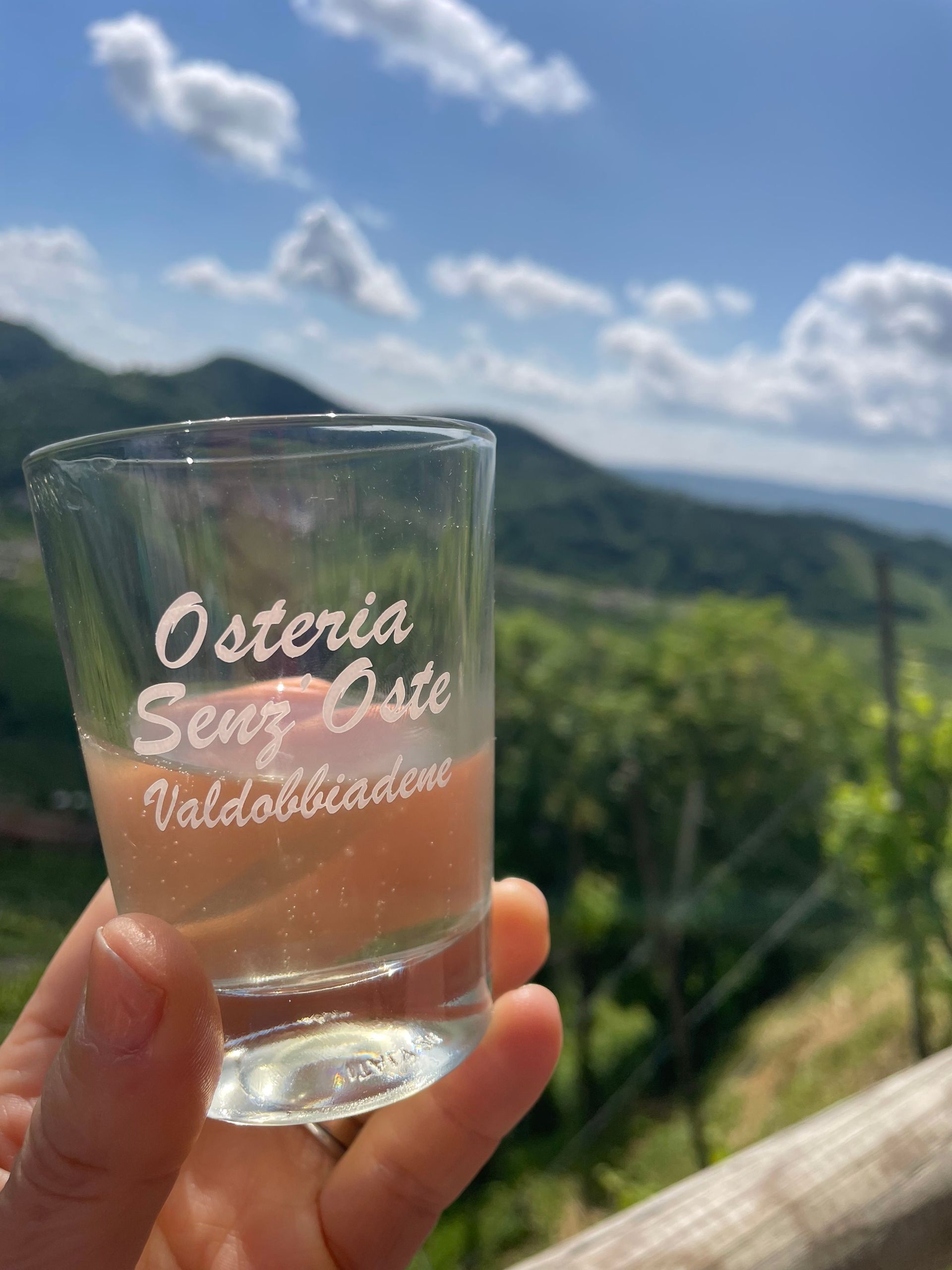 Hand holding a shot glass with pink liquid, inscribed