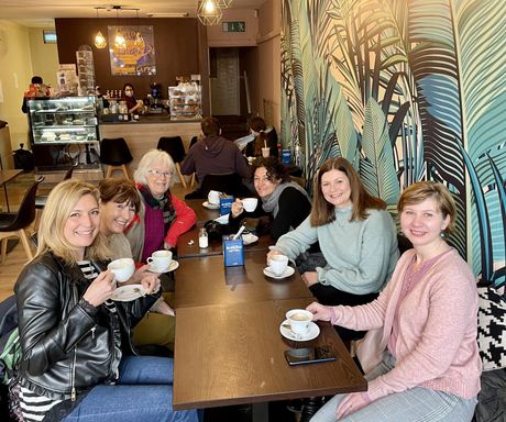 A group of women are sitting at tables in a restaurant drinking coffee.