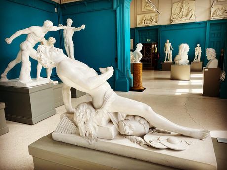 A statue of a man laying on top of a woman in a museum.
